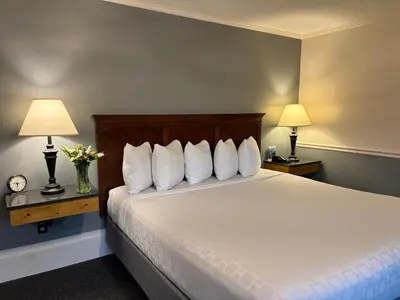 a bedroom with a bed with white pillows and two lamps at SHERWOOD MOTEL in Wellsboro