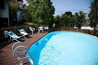 a swimming pool with two chairs and a table and chairs at Simmons Motel and Suites in Hershey