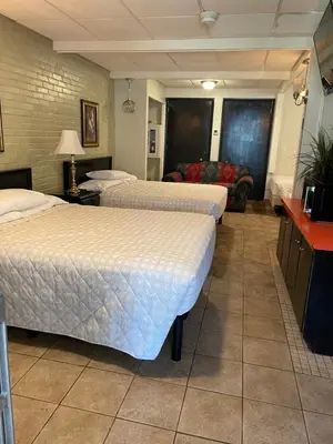 a hotel room with three beds and a couch at Simmons Motel and Suites in Hershey
