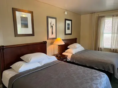 a hotel room with two beds and a lamp at Simmons Motel and Suites in Hershey