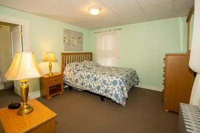 a bedroom with a bed and a table with a lamp at Simmons Motel and Suites in Hershey