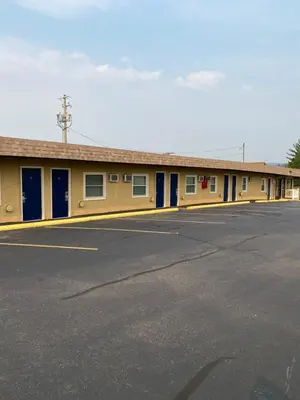 a yellow building with blue doors and a parking lot at Dunmore Inn in Dunmore