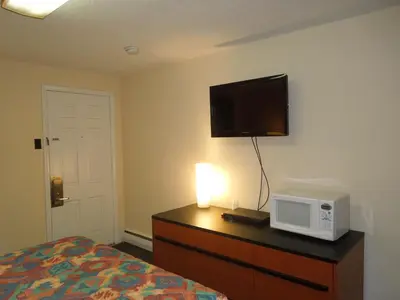a bedroom with a bed and a tv on a dresser with a microwave at Sentinel Motel in West Chester