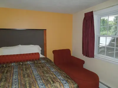 a bedroom with a bed and a chair and a window at Sentinel Motel in West Chester