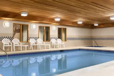 a swimming pool with white chairs and a table at Country Inn & Suites by Radisson, Lehighton-Jim Thorpe, PA in Lehighton