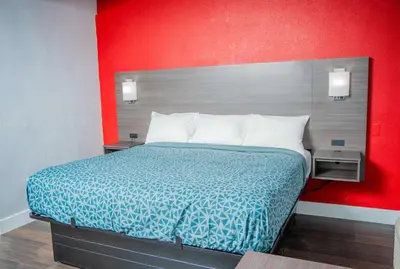 a bed in a hotel room with a red wall at Econo Lodge Clarks Summit - Scranton in Clarks Summit