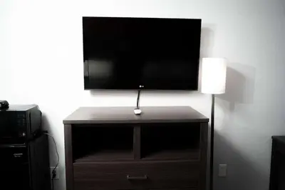a flat screen tv on top of a wooden stand with a lamp at Econo Lodge Clarks Summit - Scranton in Clarks Summit