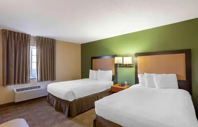 two beds in a hotel room with green walls at Extended Stay America Select Suites - Wilkes - Barre - Scranton in Wilkes-Barre