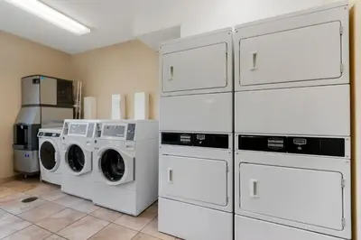 a laundry room with white cabinets and a washer and dryer at Candlewood Suites Reading by IHG in Reading