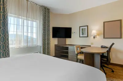 a hotel room with a bed and a desk at Candlewood Suites Reading by IHG in Reading