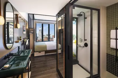 a bathroom with a shower and a sink and a bed at Moxy NYC East Village in New York