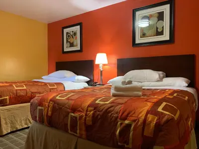 two beds in a hotel room with orange walls at Scottish Inns Wrightstown in Wrightstown
