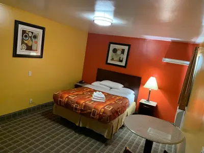 a hotel room with a bed with orange walls at Scottish Inns Wrightstown in Wrightstown