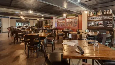 a restaurant with wooden tables and chairs and a bar at The Hub Murray Hill, BW Premier Collection in New Providence