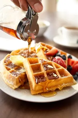 a person is pouring syrup onto a plate of waffles at Country Inn & Suites by Radisson, Frackville (Pottsville), PA in Mount Pleasant