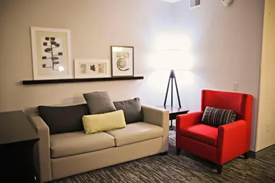 a living room with a couch and a red chair at Country Inn & Suites by Radisson, Frackville (Pottsville), PA in Mount Pleasant