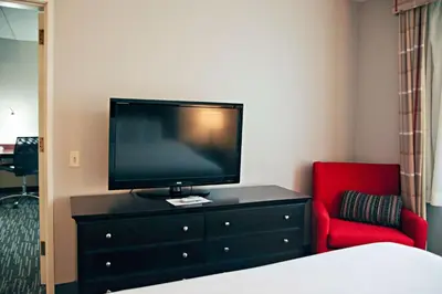 a bedroom with a tv on a dresser and a red chair at Country Inn & Suites by Radisson, Frackville (Pottsville), PA in Mount Pleasant