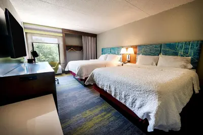 a hotel room with two beds and a flat screen tv at Hampton Inn Flemington in Flemington