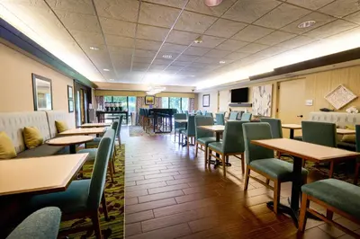 a dining room with tables and green chairs at Hampton Inn Flemington in Flemington