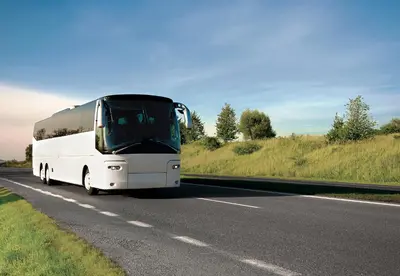 a white bus is driving down a road at Country Inn & Suites by Radisson, Lewisburg, PA in Lewisburg