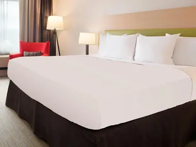 a large bed in a hotel room with a red chair at Country Inn & Suites by Radisson, Lewisburg, PA in Lewisburg