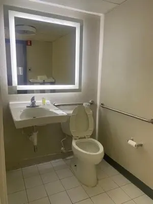 a bathroom with a toilet and a sink and a mirror at Days Inn by Wyndham Scranton PA in Dickson City