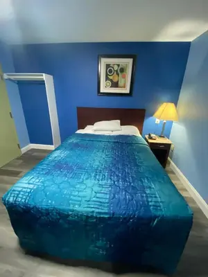 a blue bedroom with a bed with a blue wall at Red Carpet Inn & Suites Wrightstown in Wrightstown