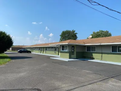 a building with a car parked in a parking lot at Red Carpet Inn & Suites Wrightstown in Wrightstown