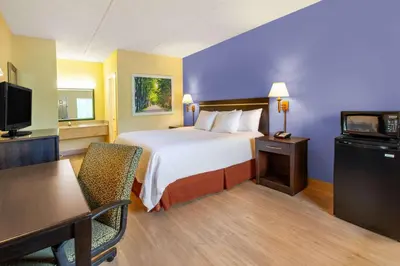 a hotel room with a bed and a desk and a television at Days Inn by Wyndham Grantville in Grantville