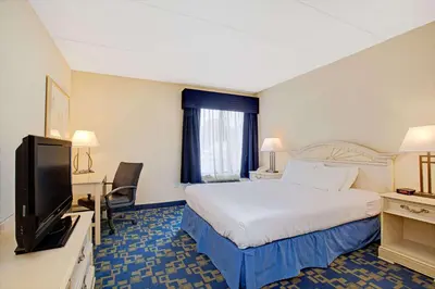 a hotel room with a bed and a flat screen tv at Windsor Hotel in East Windsor