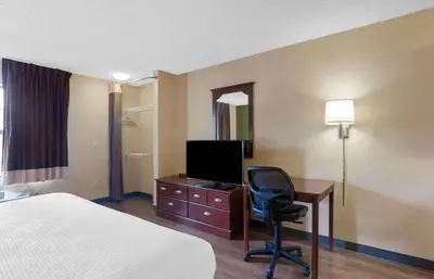 a hotel room with a bed and a desk with a television at Extended Stay America Suites - Somerset - Franklin in Somerset