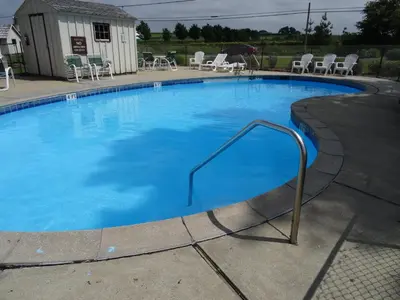 a large swimming pool with blue water and chairs at Amish Country Motel in Bird in Hand