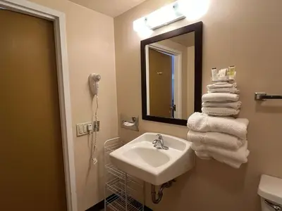 a bathroom with a sink and a mirror and towels at Travelodge by Wyndham Hershey in Hershey