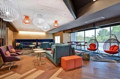 a lobby with chairs and tables and windows at Tru By Hilton Middletown in Middletown