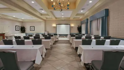a conference room with white tables and chairs and a screen at Radisson Hotel Freehold in Freehold