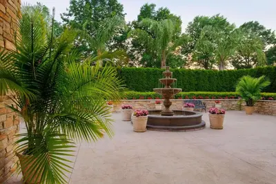 a fountain in a courtyard with palm trees and plants at Radisson Hotel Freehold in Freehold