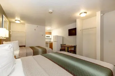 a hotel room with two beds and a table at HomeTowne Studios by Red Roof Philadelphia - Maple Shade, NJ in Maple Shade