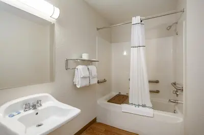 a white bathroom with a sink and a shower at HomeTowne Studios by Red Roof Philadelphia - Maple Shade, NJ in Maple Shade