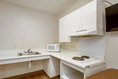 a white kitchen with a sink and a microwave at HomeTowne Studios by Red Roof Philadelphia - Maple Shade, NJ in Maple Shade