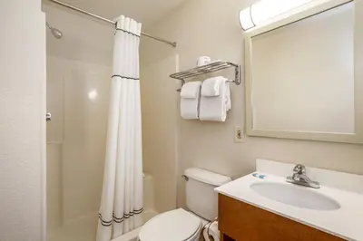 a bathroom with a toilet and a sink and a mirror at HomeTowne Studios by Red Roof Philadelphia - Maple Shade, NJ in Maple Shade