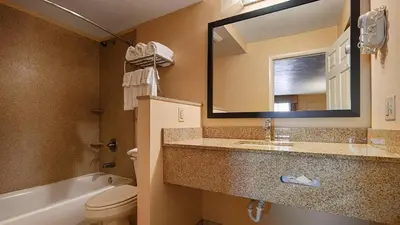 a bathroom with a sink and a toilet and a mirror at Quality Inn & Suites Williamsport in Williamsport