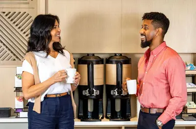 a man and a woman standing in a kitchen holding coffee cups at Hyatt House Morristown in Morristown