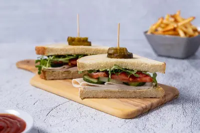 two sandwiches on a cutting board with a bowl of fries at Hyatt House Morristown in Morristown