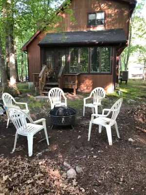 four white chairs and a fire pit in front of a cabin at My Little Flagship Cabin in East Stroudsburg