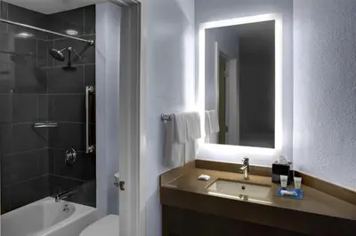 a bathroom with a sink and a tub and a mirror at Hyatt House Branchburg - Bridgewater in Branchburg Park
