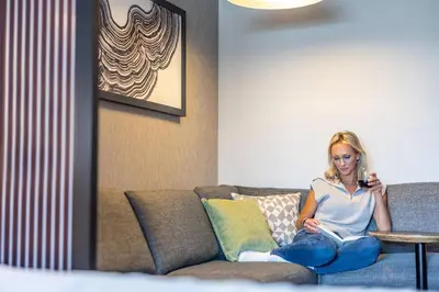 a woman sitting on a couch reading a book at Hyatt House Branchburg - Bridgewater in Branchburg Park