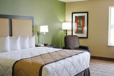 a hotel room with a large bed and a chair at Extended Stay America Suites - Newark - Woodbridge in Woodbridge