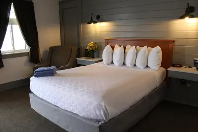 a hotel room with a large bed with white pillows at Canyon Motel in Wellsboro