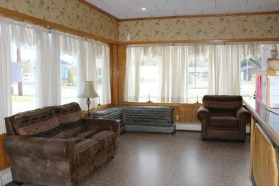 a living room with a couch and chairs and windows at Canyon Motel in Wellsboro