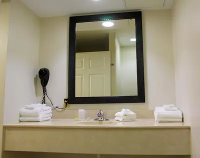 a bathroom with a sink with a mirror and towels at Canyon Motel in Wellsboro